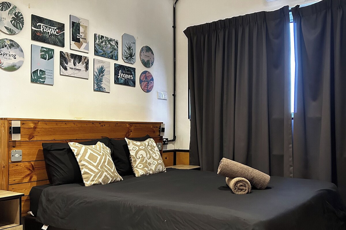 A bedroom with a wooden headboard, a black bedspread, and decorative wall art.