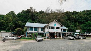 A building with a sign reading "Riverbank Dungun" with several parked cars in front. - Riverbank Dungun Guesthouse & Cafe (Dungun)