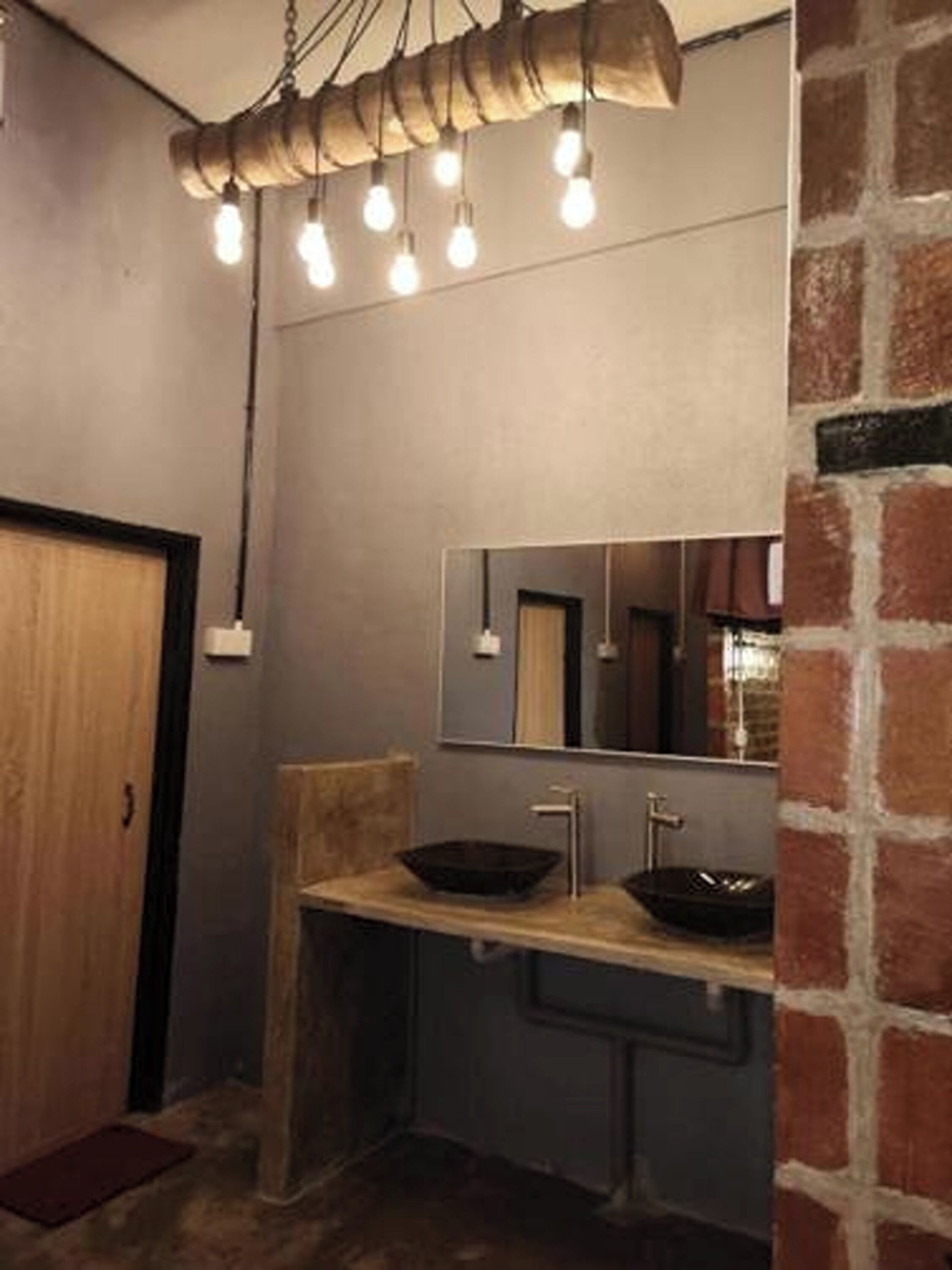 A bathroom with a wooden vanity, a large mirror, and a unique light fixture above the sink.