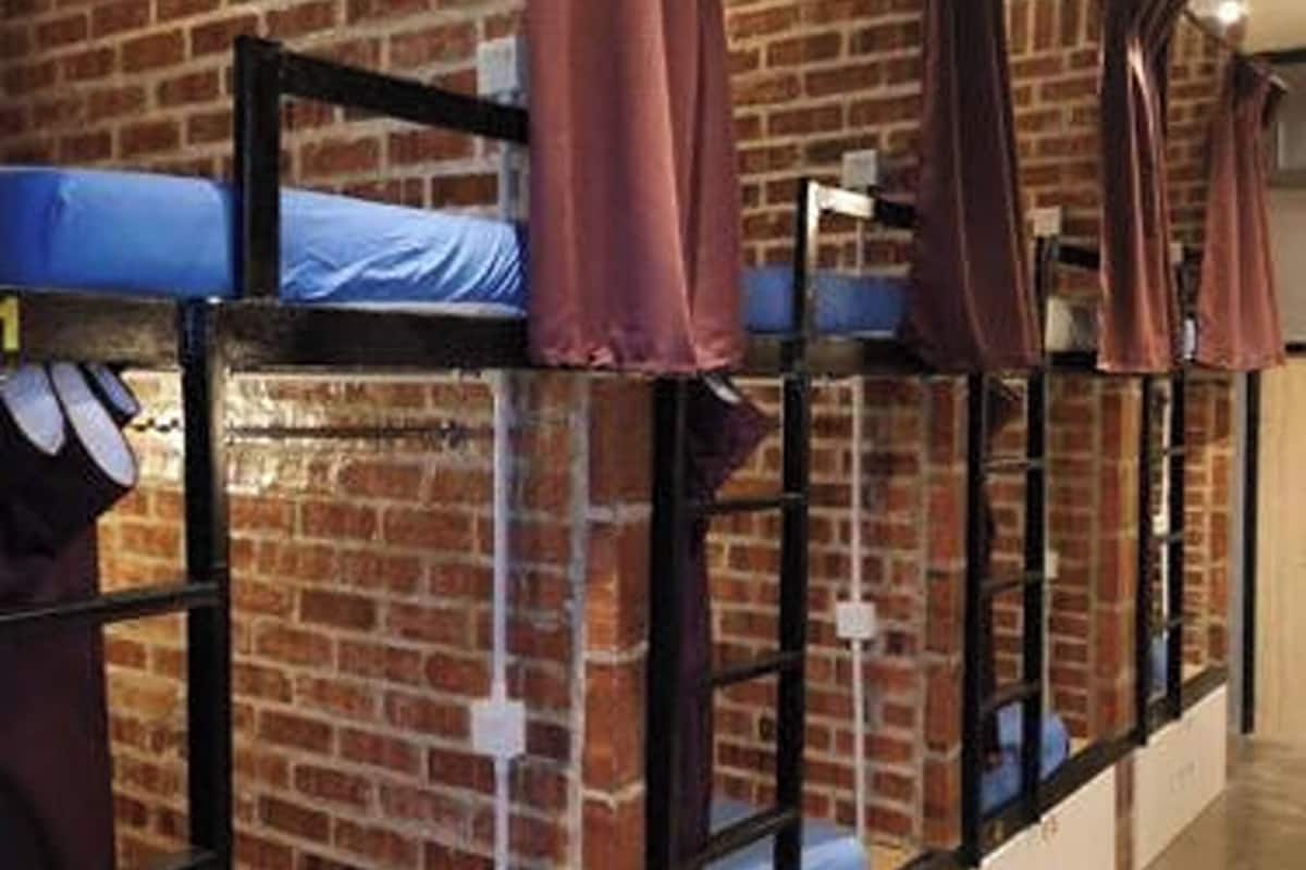 A hostel room with bunk beds, brick walls, and a simple, functional design.