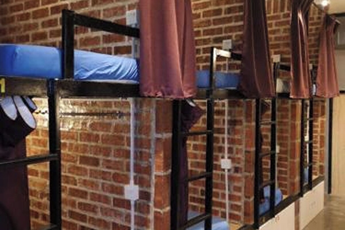 A hostel room with bunk beds, brick walls, and a simple, functional design.