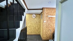 Un pasillo con una escalera, una pared de madera con un letrero y una escoba apoyada en la pared.