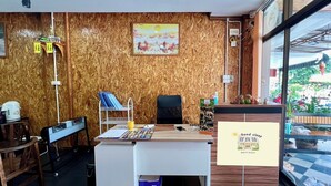 Una recepción con un letrero que dice 'Buen descanso', paneles de madera, un cuadro y vistas al exterior a través de amplias ventanas.