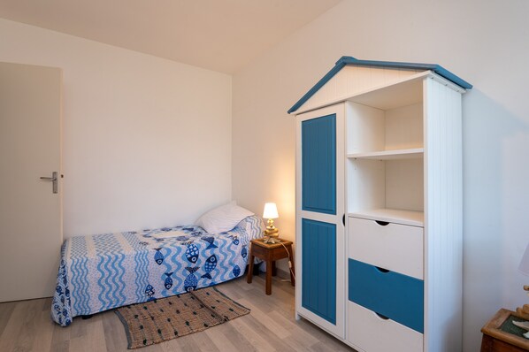 A bedroom with a bed, a bedside table with a lamp, a wardrobe, and a door.