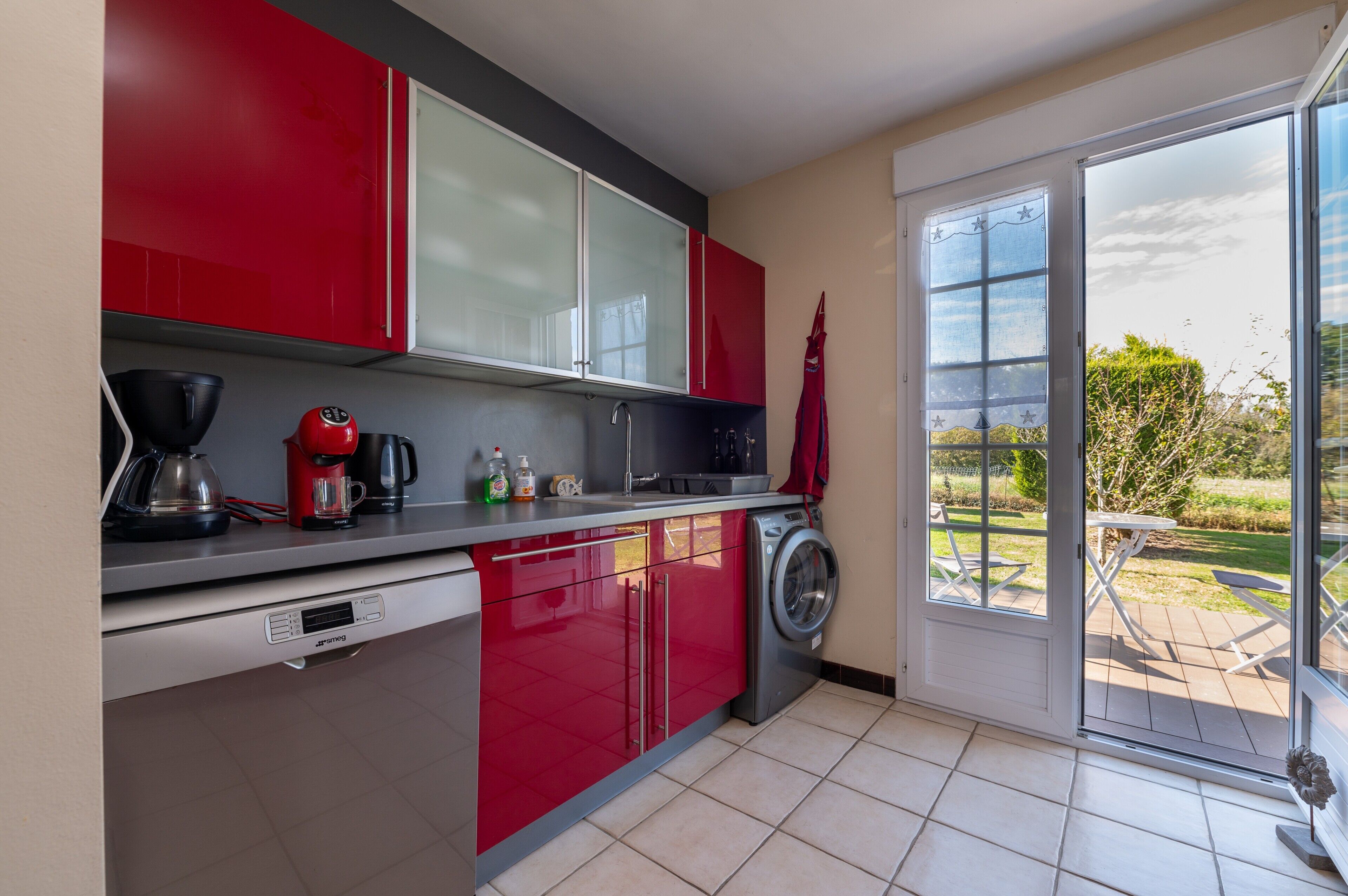 A kitchen with red cabinets, a washing machine, and a coffee maker.