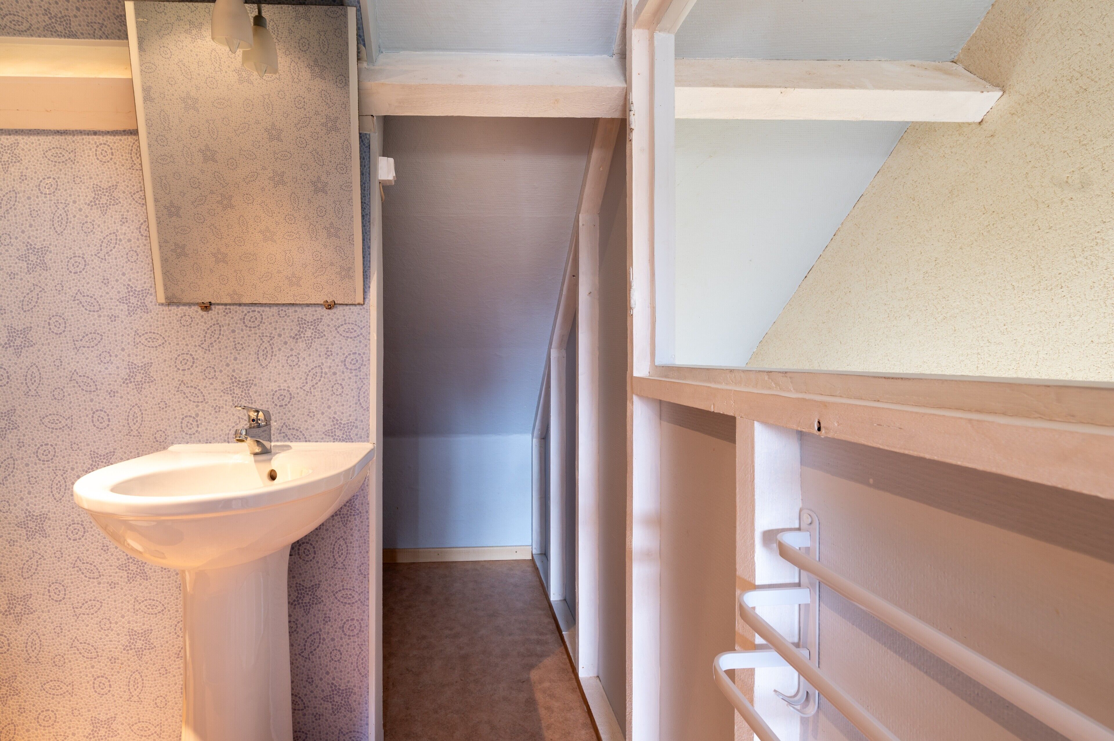 A bathroom with a sink, towel rack, and a shower area.