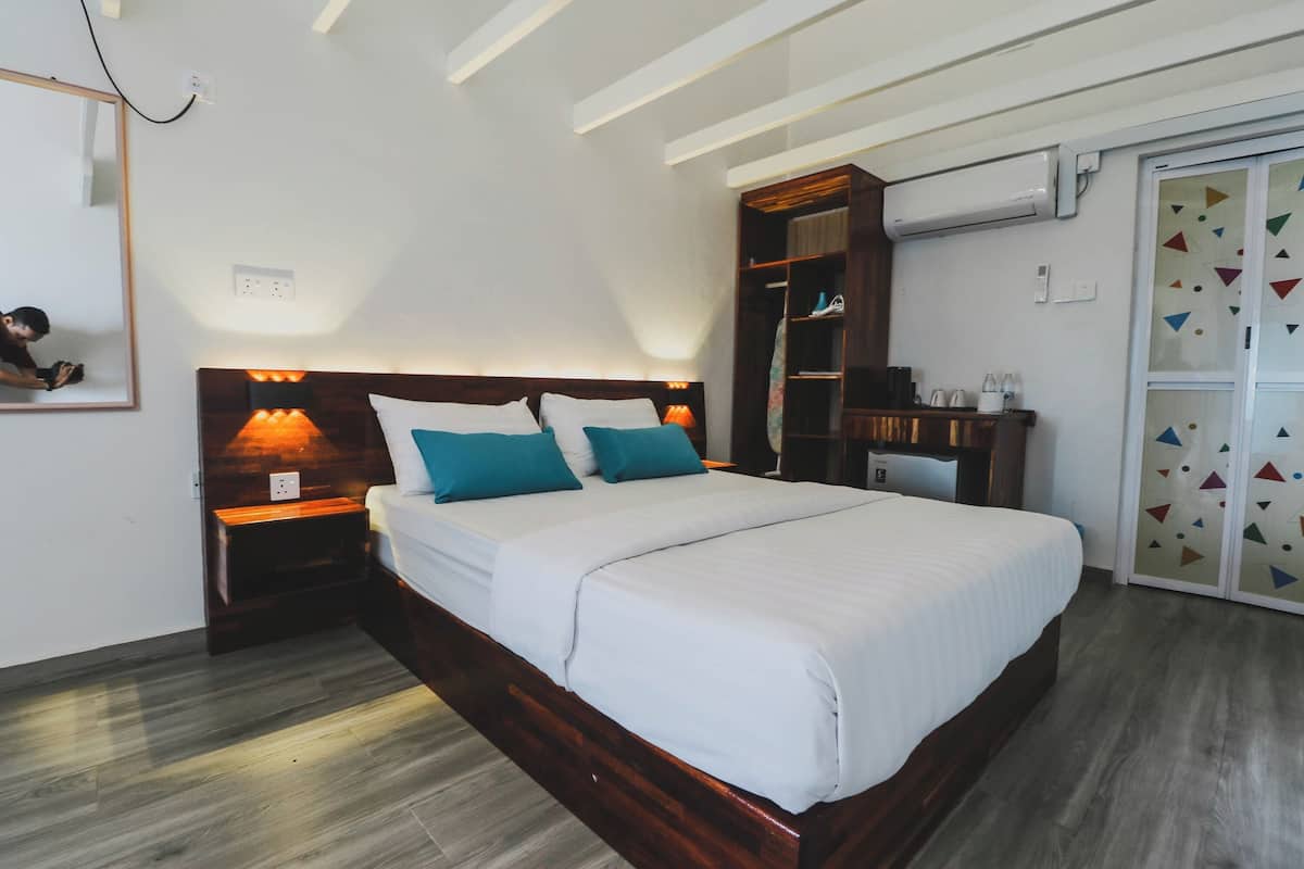 Un dormitorio con una cama de madera, dos lámparas de noche, un armario y un espejo.