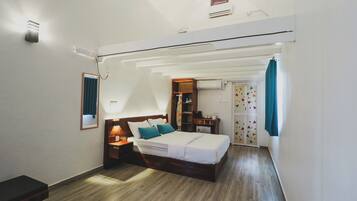 Un dormitorio con cama, mesitas de noche, un armario y un escritorio pequeño con silla.