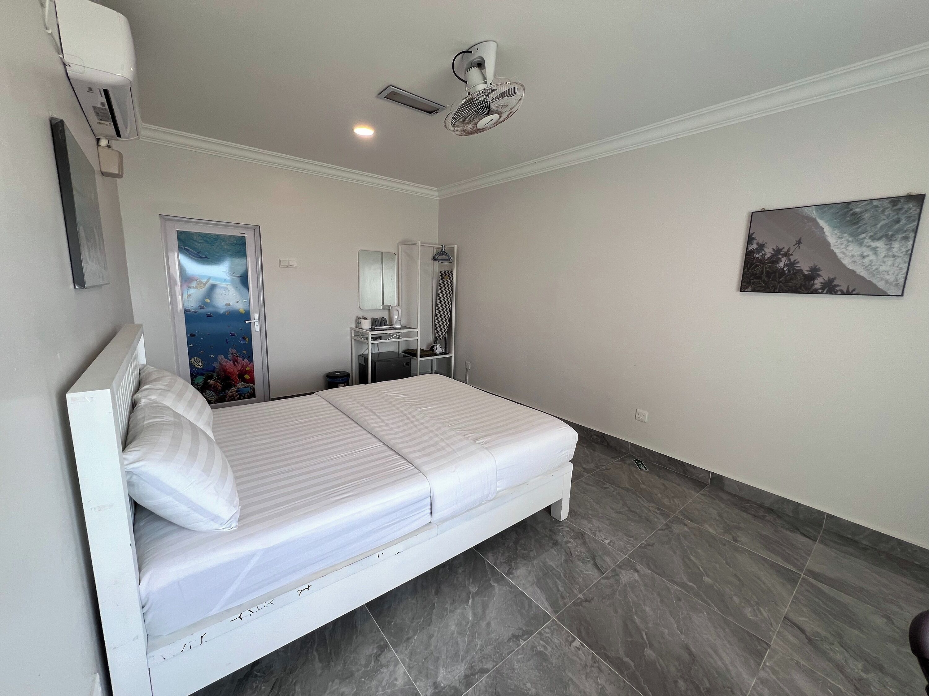 A bedroom with a bed, a desk with a chair, a mirror, an air conditioner, and a ceiling fan.