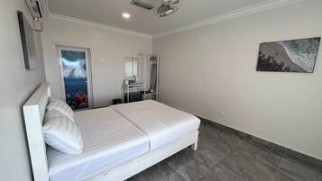 A bedroom with a bed, a desk with a chair, a mirror, an air conditioner, and a ceiling fan.