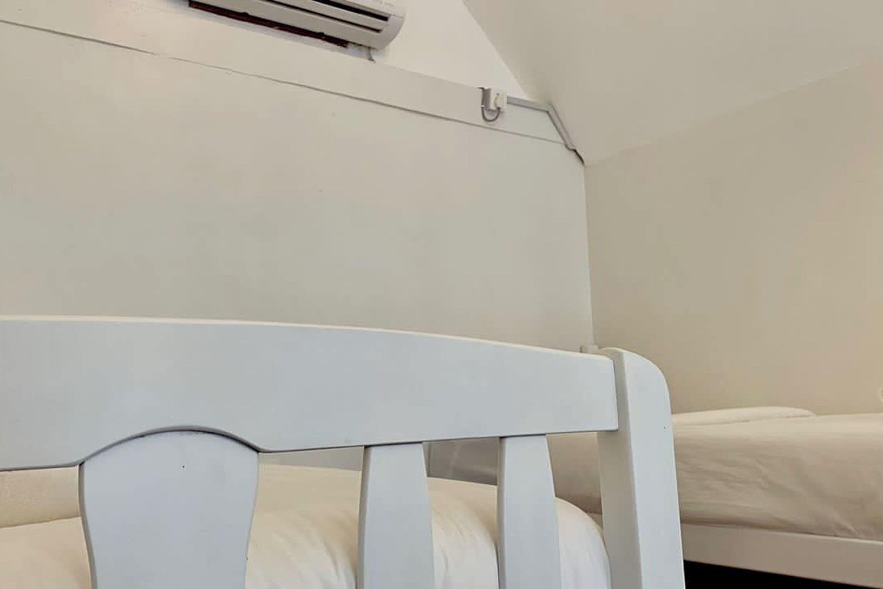 Um berço branco com colchão branco, parede branca e teto branco.