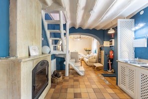 A kitchen with a fireplace, a staircase, and a dining area with a sofa. - Country House Villa Florita with Private Pool near Chinchón and Aranjuez (VALDELAGUNA)