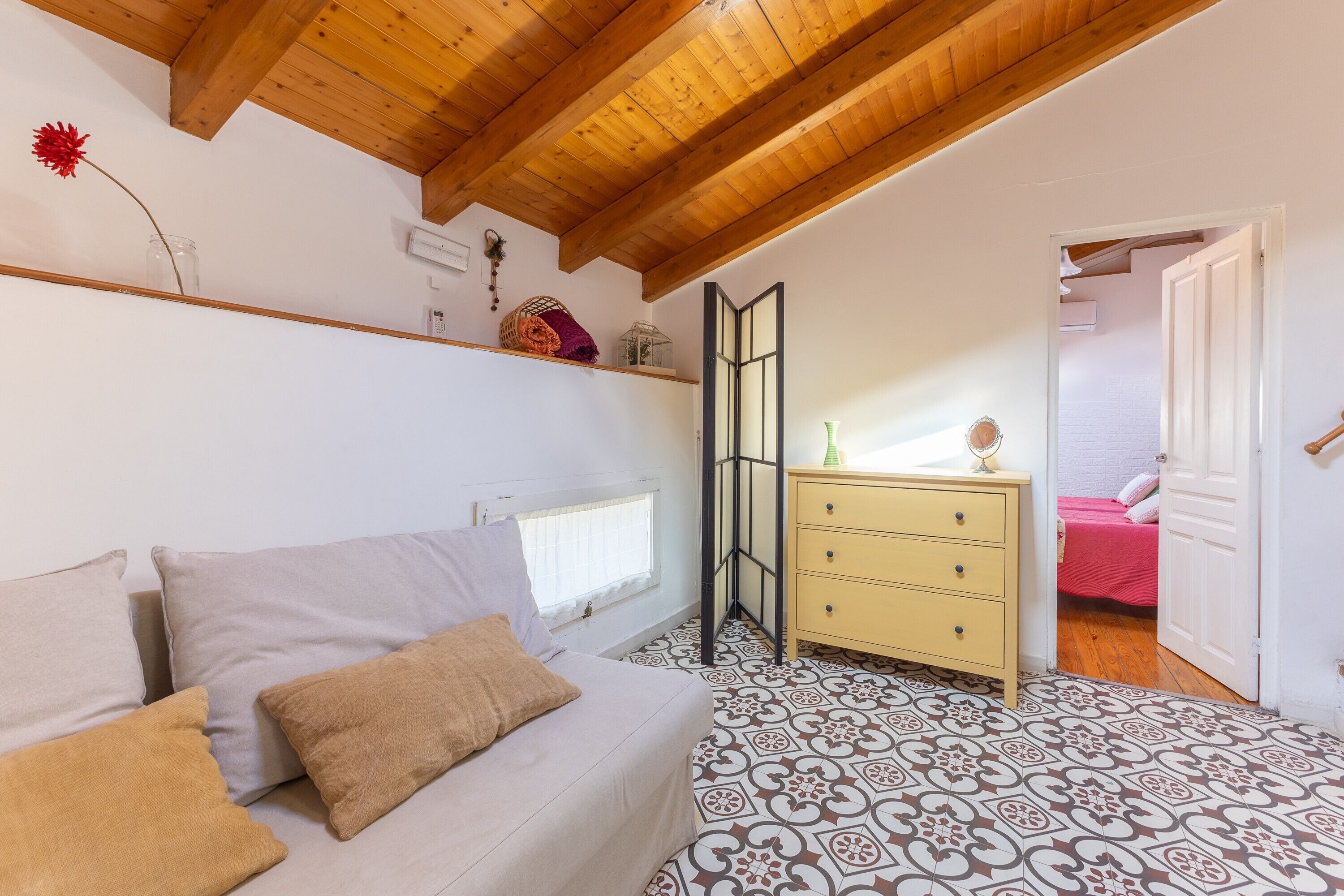Een slaapkamer met een bed, een dressoir, een spiegel en een raam.