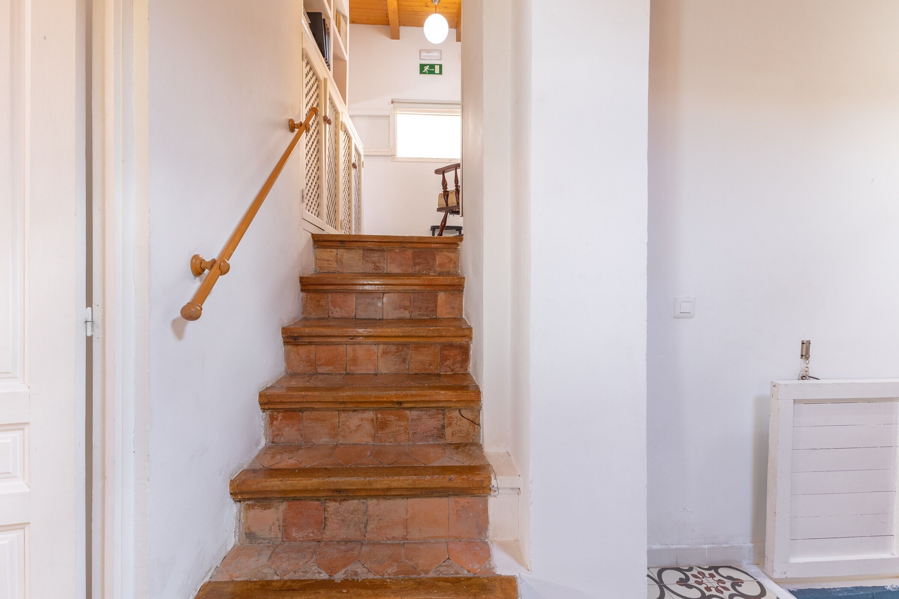 Un escalier avec une rampe en bois et un mur blanc.