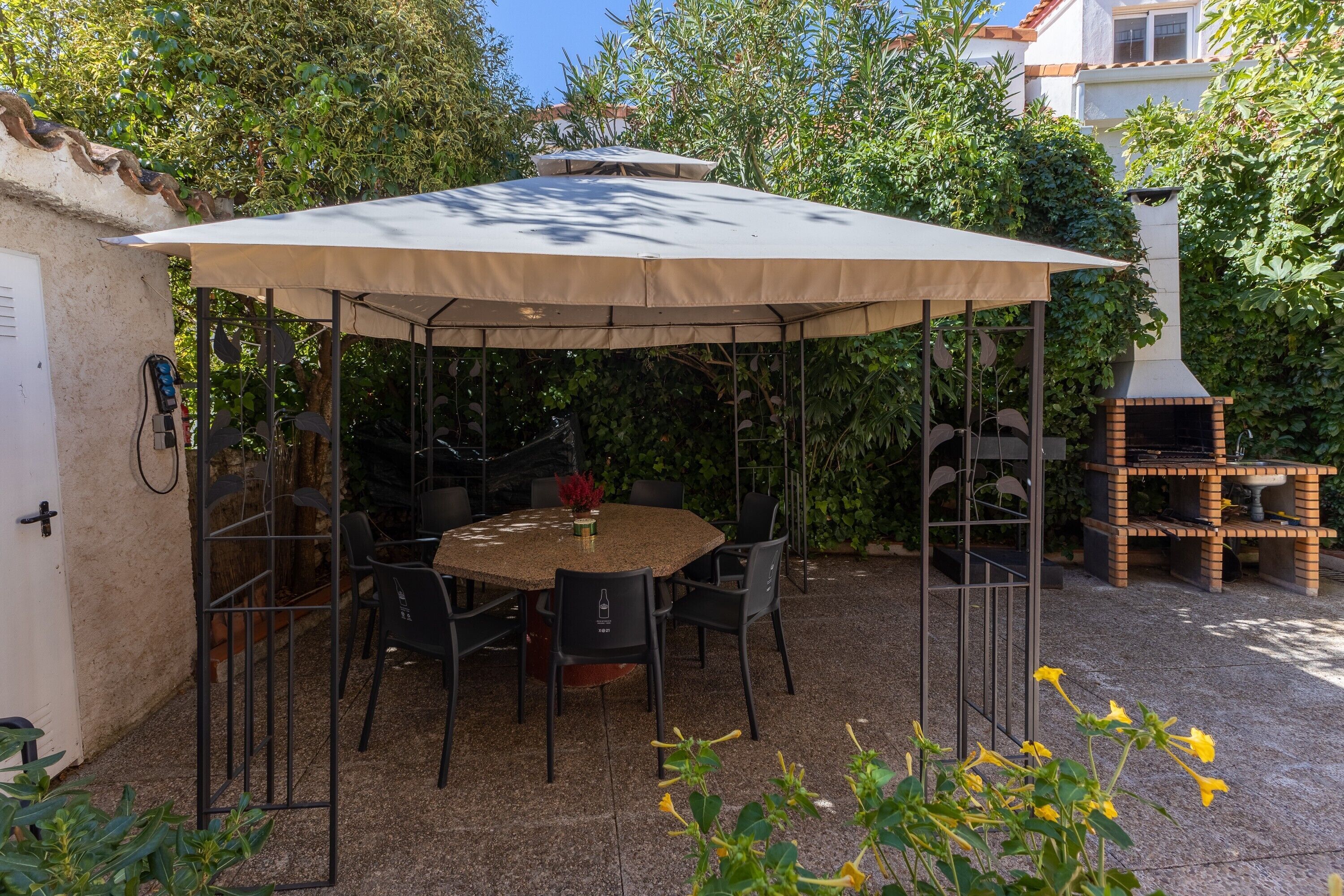 An outdoor patio with a round table, chairs, and a large umbrella.