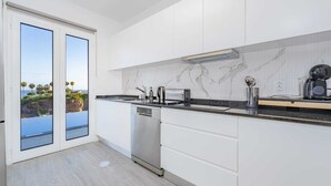 A modern kitchen with white cabinets, a stainless steel dishwasher, and a black countertop. - Where Serenity Meets Blue Horizons.  (Câmara de Lobos)