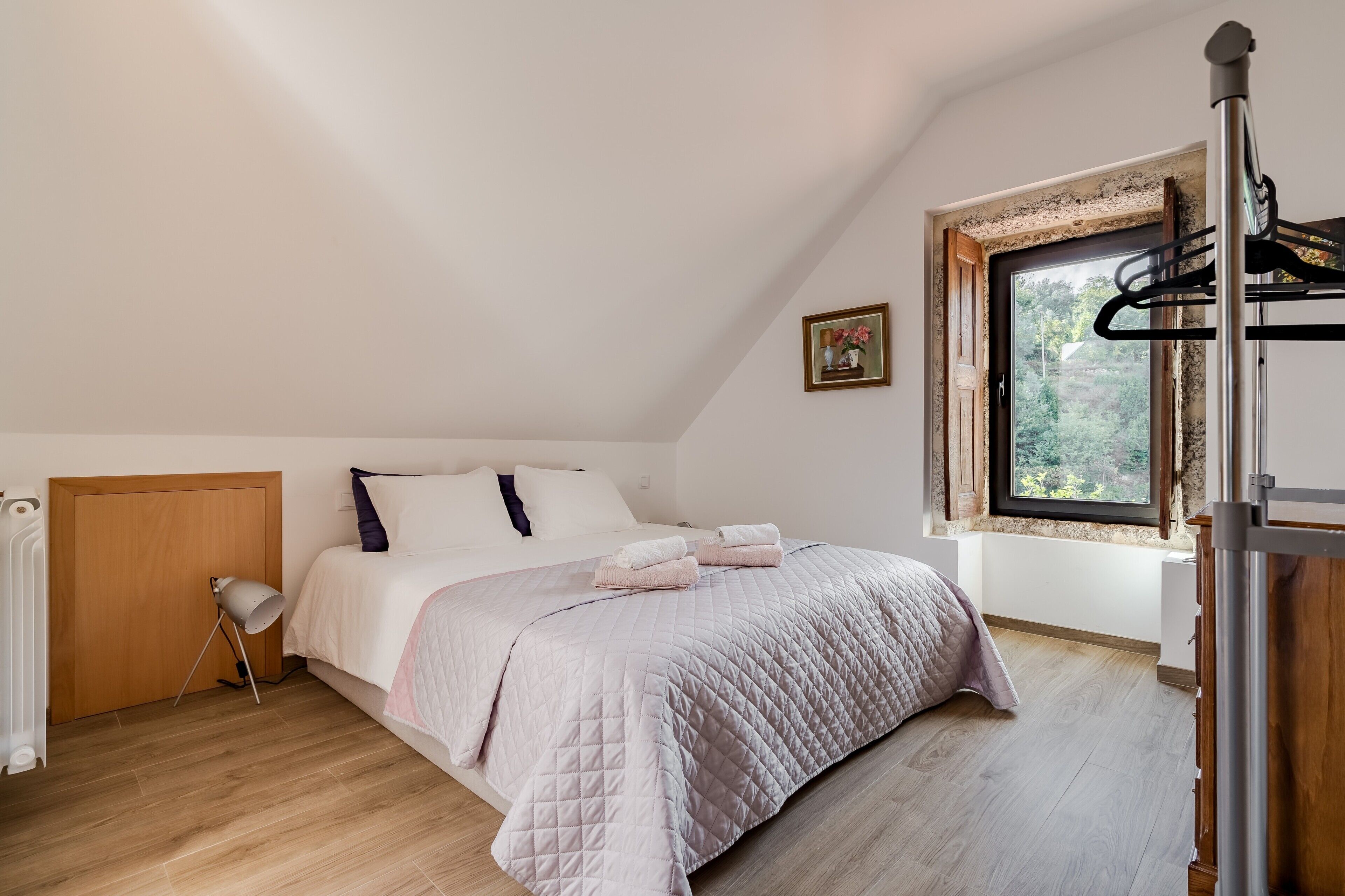 Een slaapkamer met een bed, een radiator, een raam en een houten vloer.