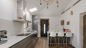 Una cocina moderna con horno integrado, cafetera y comedor con mesa y sillas.