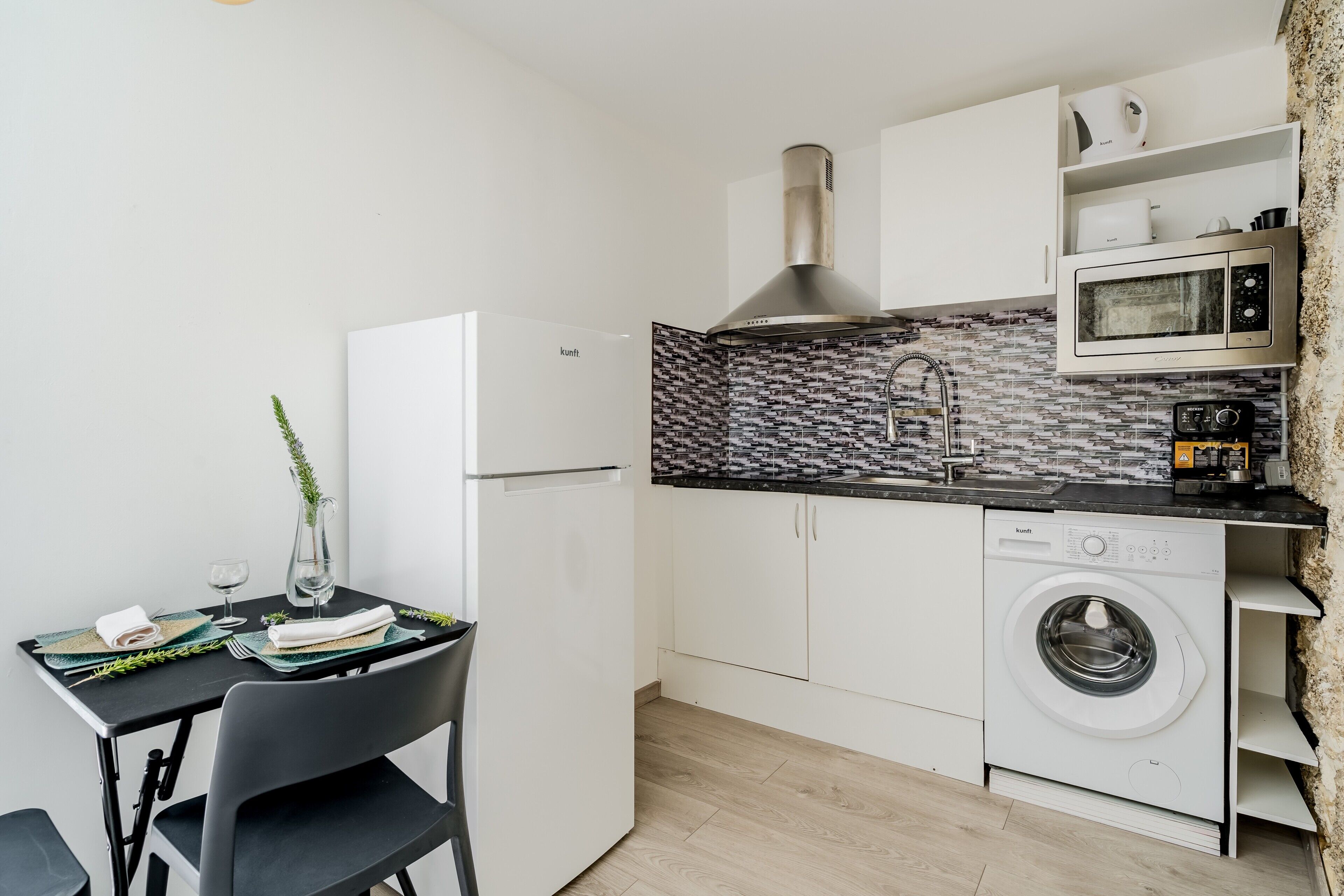 Une cuisine compacte équipée d’un lave-linge, d’un four à micro-ondes et d’un évier.