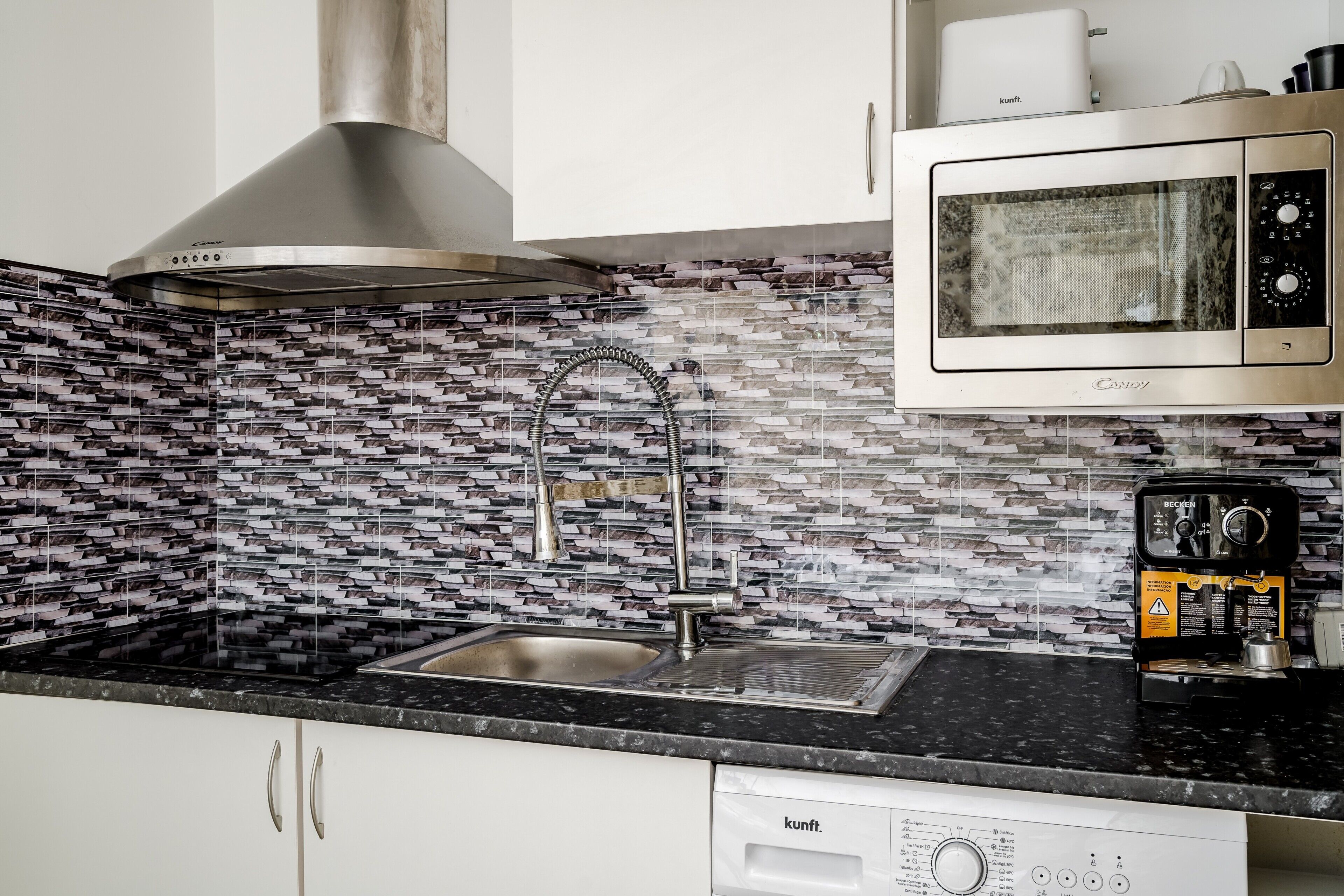 A kitchen with a stainless steel range hood, a microwave, and a coffee maker.