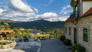 A stone building with a red-tiled roof, a balcony, and a view of a mountainous landscape. - Studio Apartment 'Quinta Do Bairro -' with Mountain View, Shared Pool and Wi-Fi (Rossas)