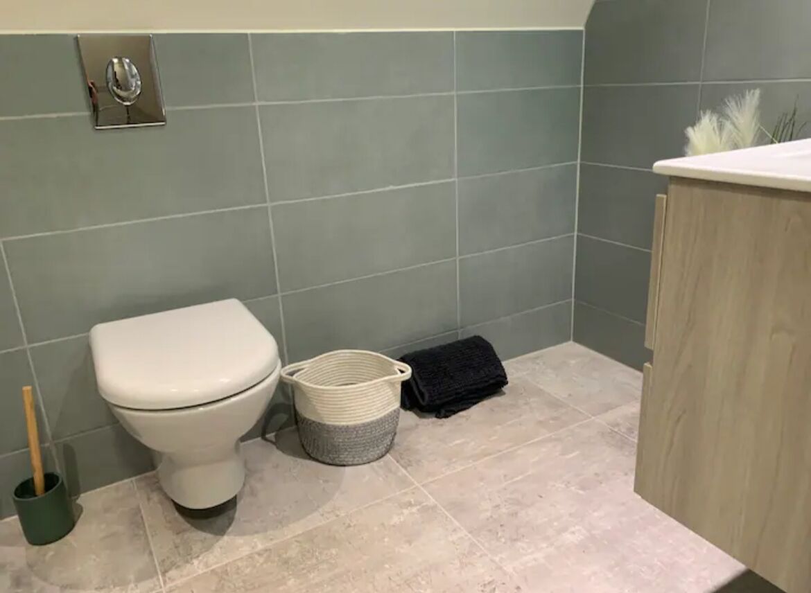 Un baño con un inodoro, una cesta y una toalla en el suelo.