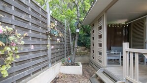 A wooden deck with a bench, a small garden area with plants and flowers, and a wooden fence. - Fully Equipped Chalet V Near the Sea with Shared Pool, Private Terrace, and Air Conditioning (Pianottoli-Caldarello)