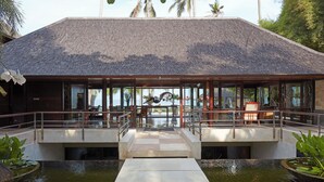 A modern building with a tiled roof, glass windows, and a water feature in front.