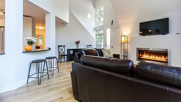 Una sala de estar moderna con chimenea, un sofá y un televisor montado en la pared.