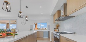 Une cuisine moderne avec des meubles en bois, une cuisinière en acier inoxydable et des luminaires suspendus.