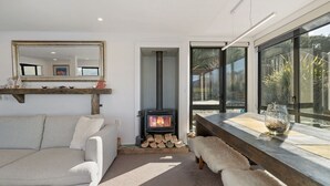 Un salon moderne doté d’une cheminée, d’un canapé, d’un banc et d’une grande fenêtre donnant sur l’extérieur.
