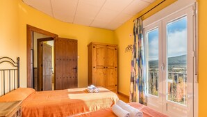 A room with a bed, a wooden wardrobe, a window with a view, and a door. - Apartment 'Postero' with Mountain View, Balcony and Wi-Fi (Jérez del Maquesado)