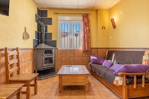 Una sala de estar con un sofá, una mesa de madera, una chimenea y un ventanal con cortinas.