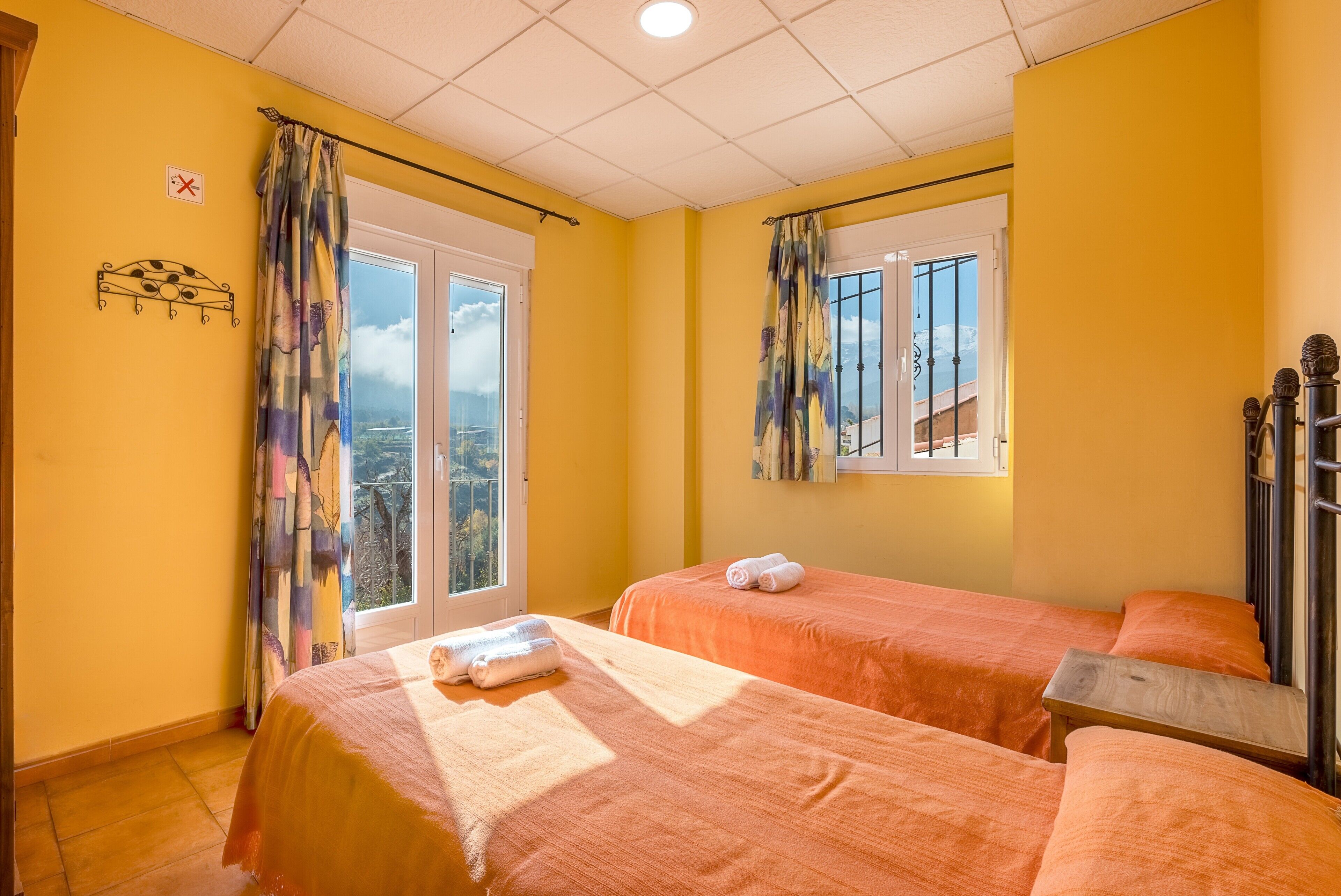 Een kamer met twee bedden, een raam, een balkon en een deur.