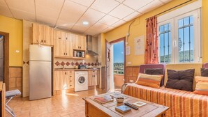 A compact living space with a kitchenette, a sofa, and a dining table. - Apartment 'Tizná' with Mountain View, Shared Terrace and Wi-Fi (Jérez del Maquesado)