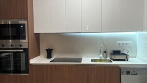 Een moderne keuken met houten kastjes, een inbouwoven, een magnetron, een spoelbak en een vaatwasser.