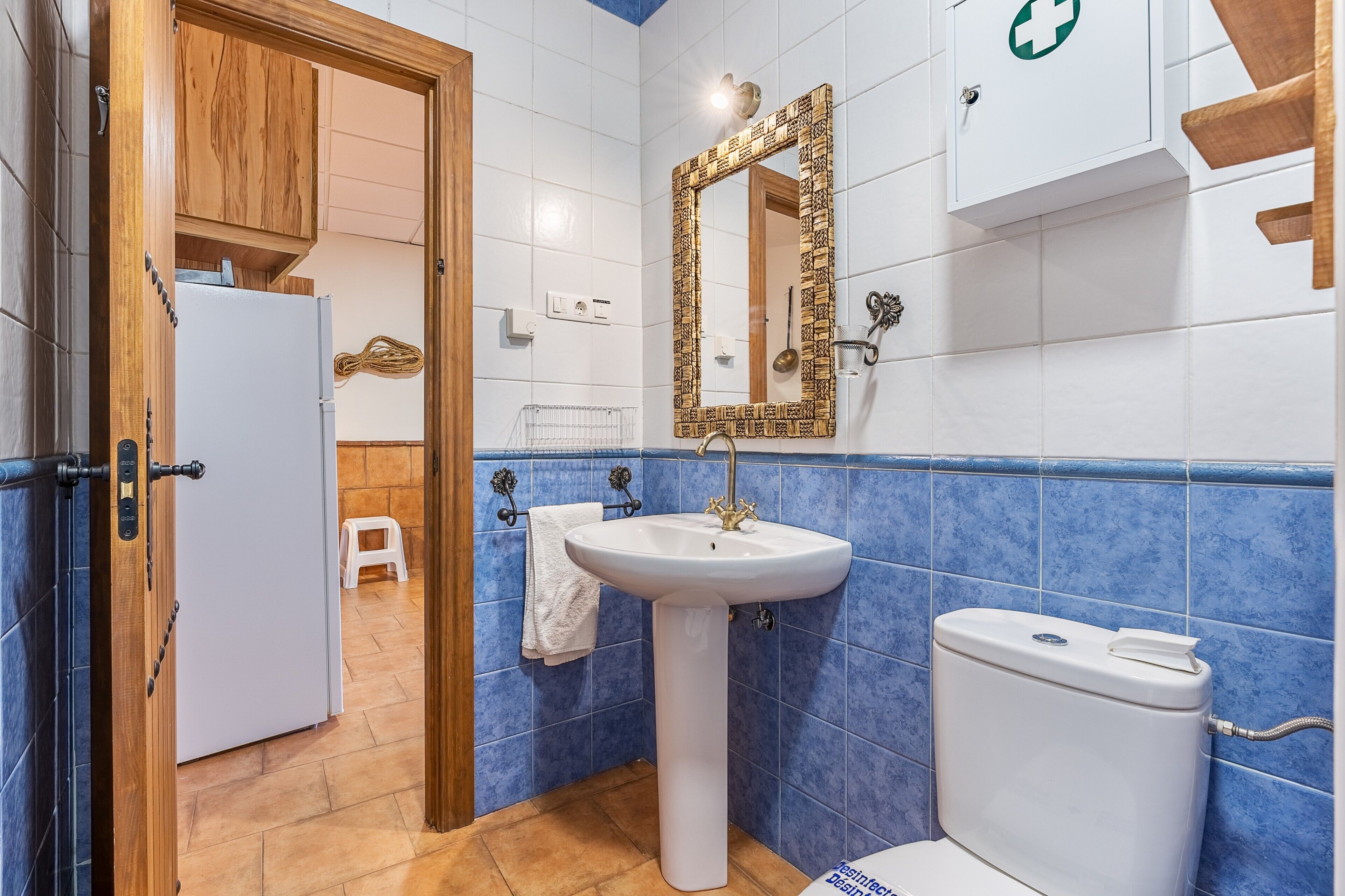 A bathroom with a white sink, a toilet, and a mirror with a decorative frame.