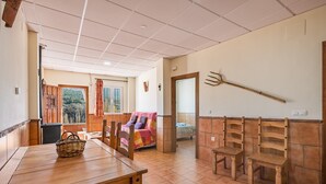 Un comedor con mesas y sillas de madera, una cesta de mimbre y vistas por una ventana.