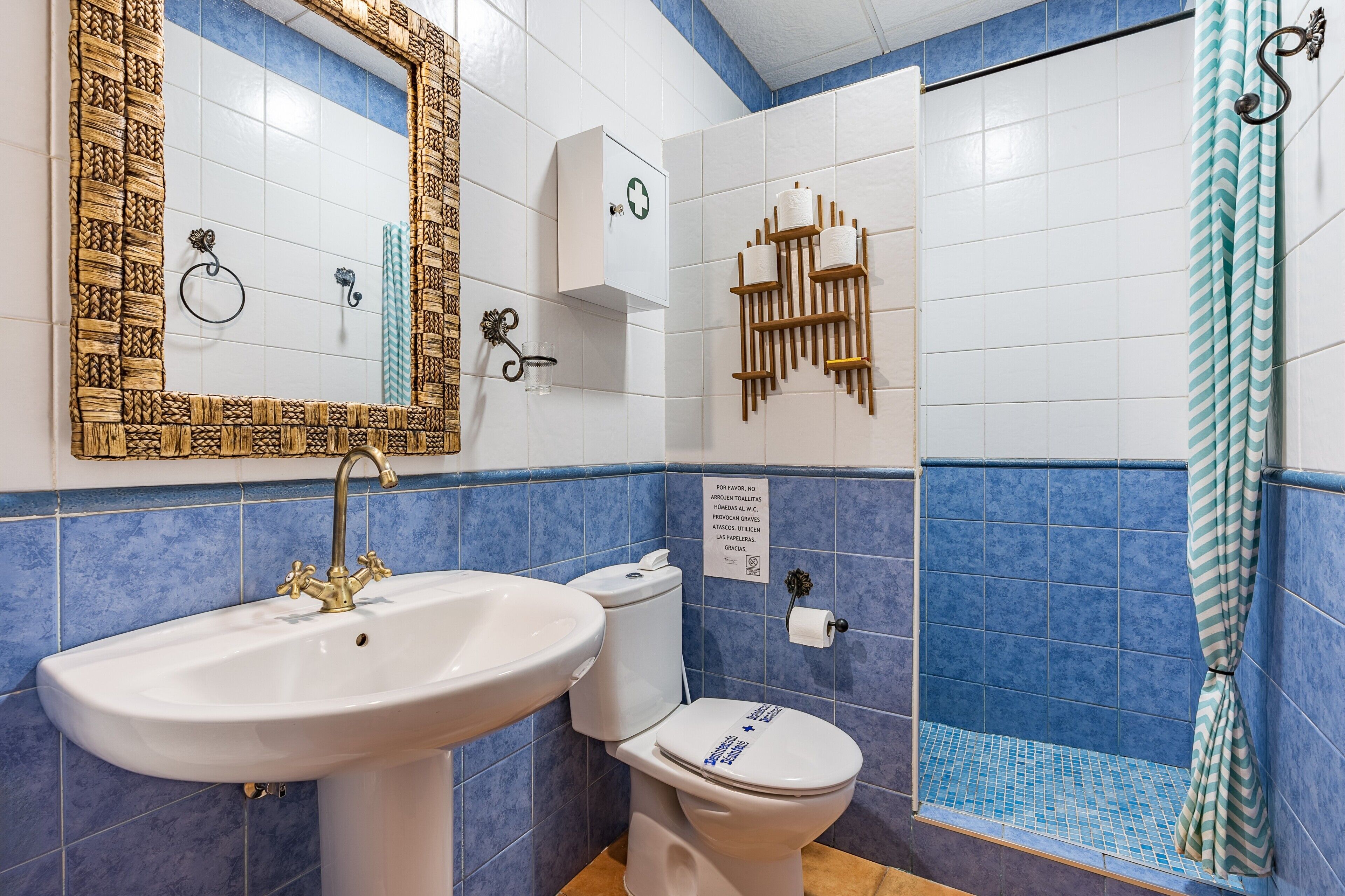 A bathroom with a sink, toilet, mirror, and shower.