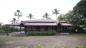 A two-story building with a red roof and a covered porch. - Rockhill Adventures And Resorts (Roha)