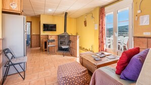 Una habitación acogedora con sofá, una mesita, televisión, chimenea y vistas al exterior.