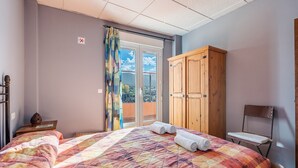 Un dormitorio con cama, armario de madera, una silla y vista al exterior.