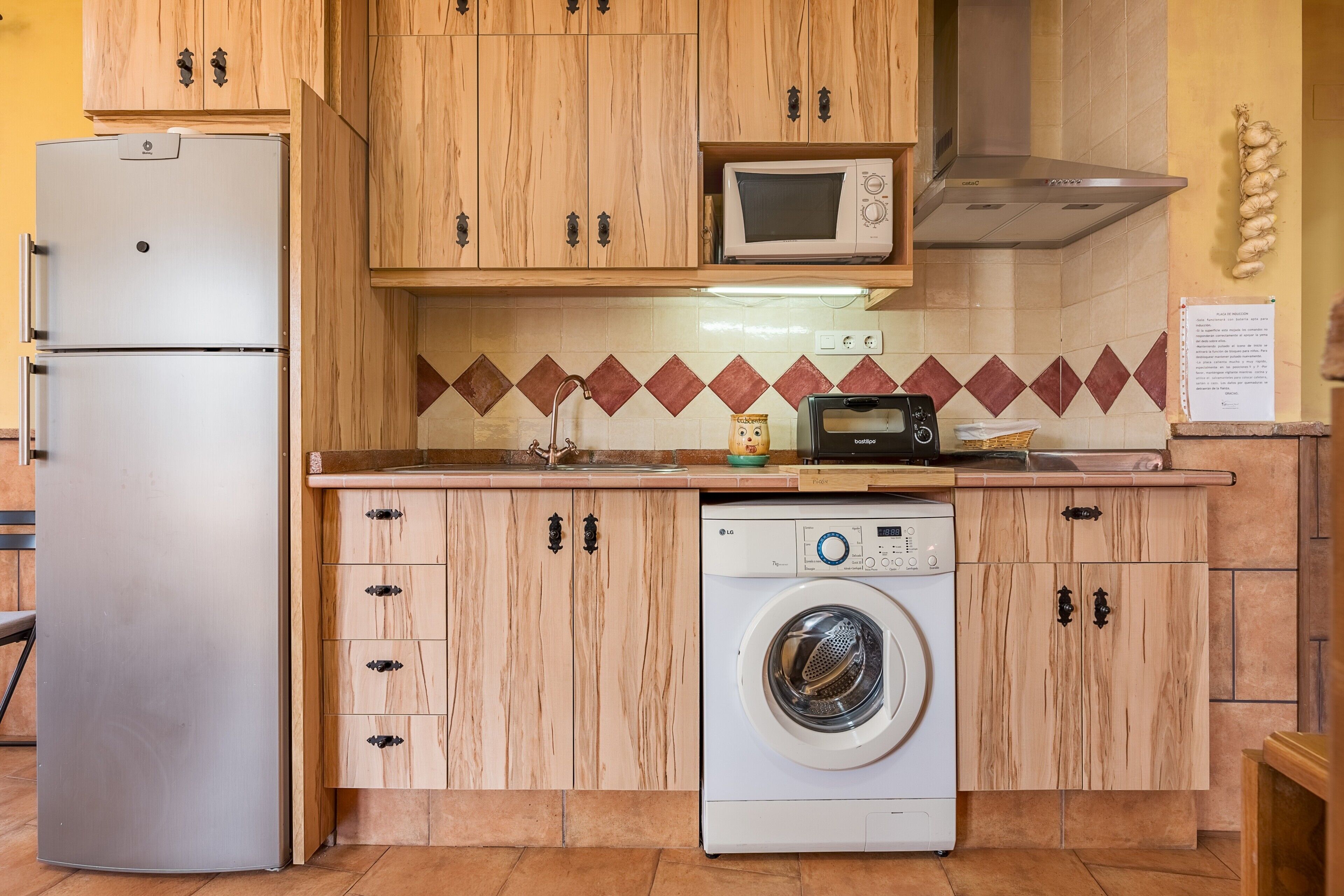 Eine kompakte Küche mit Kühlschrank, Mikrowelle, Toaster und Waschmaschine.