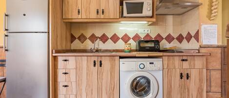 Eine kompakte Küche mit Kühlschrank, Mikrowelle, Toaster und Waschmaschine.