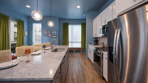 Una cocina moderna con encimera de mármol, electrodomésticos de acero inoxidable y un banco de madera.
