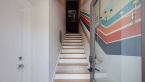 A staircase with wooden steps and a glass door at the bottom. - 2BR Near DT — Rooftop Deck + Fire Pit + Sleeps 7 (Nashville)