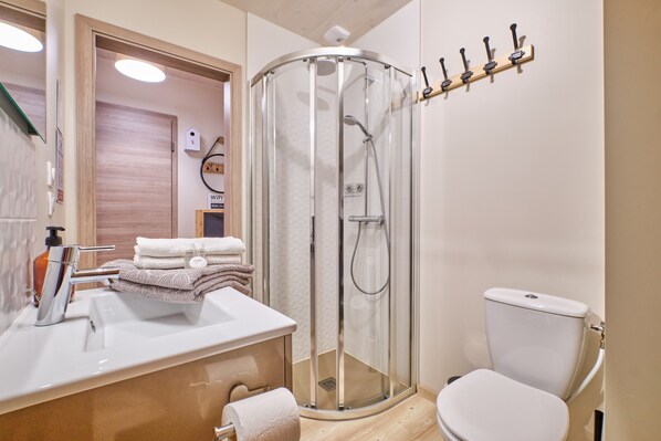 A bathroom with a glass-enclosed shower, a white sink, and a toilet.