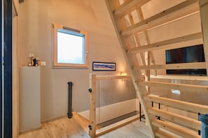 A room with a sloped ceiling, a window with a view, a framed picture on the wall, and a wooden bench. - Chalet 'L'Ecrin De Venosc' with Mountain View, Private Terrace and Wi-Fi (Les Deux Alpes)