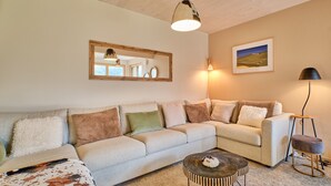 A living room with a sectional sofa, a coffee table, a lamp, and a framed picture on the wall.