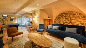 A spacious living area with a stone wall, a blue sofa, a wooden coffee table, and a pool table.